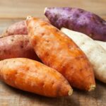 Diverses variétés de patates douces fraîches disposées sur une table en bois rustique