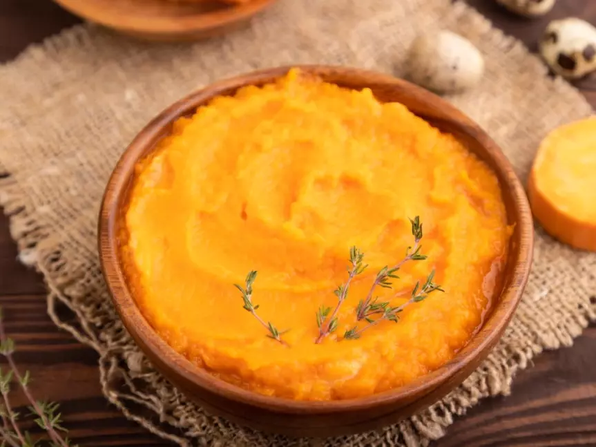 Purée de patate douce crémeuse servie dans un bol avec une noix de beurre fondante